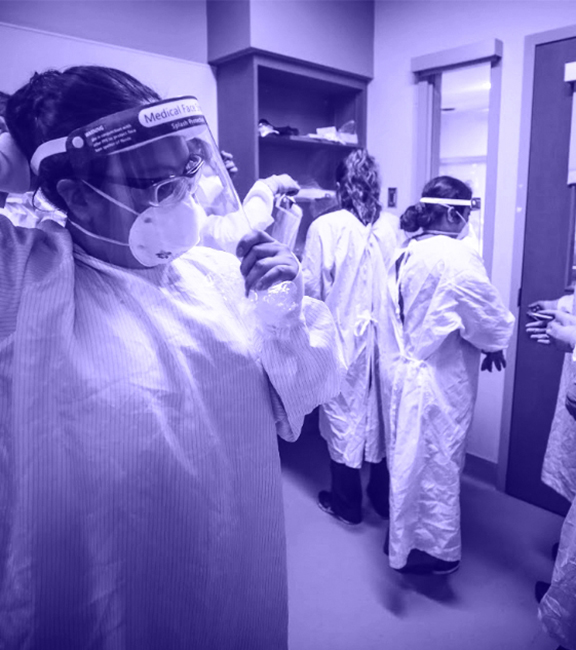 Health care workers in a room putting on personal protective equipment (PPE)