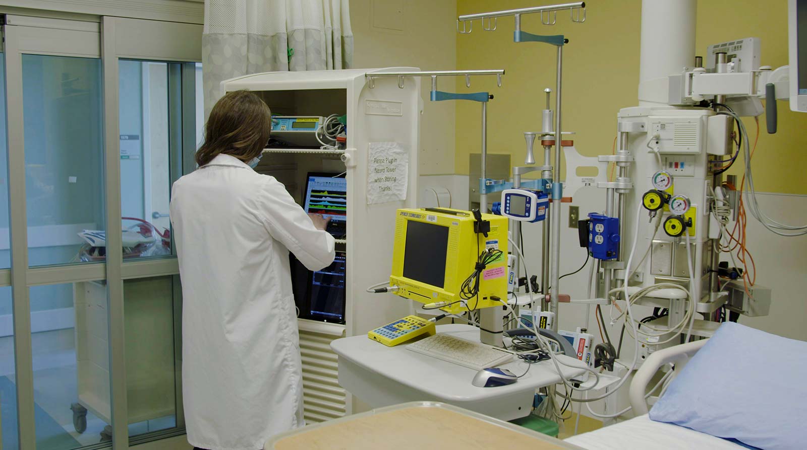 Health care worker in a room with many machines and working on a computer